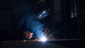 The image shows a welder wearing a protective helmet, illustrating how to choose the right welding helmet for safety.