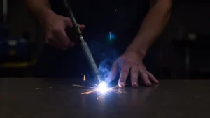 The image shows a close-up of a TIG welder setup for thin sheet metal welding.