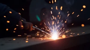 The image shows a MIG welder's output with excessive spatter, illustrating the blog post topic.